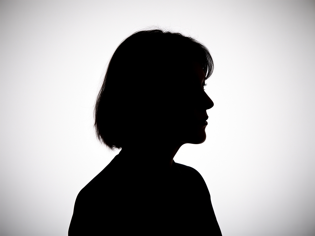 Silhouette d'une personne en position de méditation au sommet d'une colline herbeuse au lever du soleil, ciel dégradé orange et rose, paysage calme et contemplatif